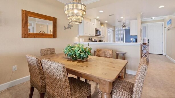 A dining area with a wooden table, wicker chairs, a chandelier, and a kitchen in the background. - Enjoy a serene harbor view in this spacious 2-bedroom condo in Placida. (Placida)