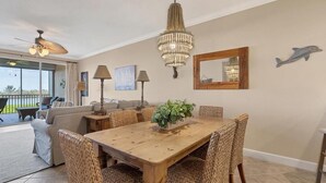 A dining area with a wooden table and wicker chairs, a chandelier, and a ceiling fan. - Enjoy a serene harbor view in this spacious 2-bedroom condo in Placida. (Placida)