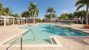 A large outdoor swimming pool with clear blue water, surrounded by palm trees and lounge chairs. - Stay in comfort at Landings 126 in Placida: a spacious 3BR retreat! (Placida)