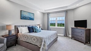 A bedroom with a large bed, a TV, a nightstand, a lamp, and a window with curtains. - Stay in comfort at Landings 126 in Placida: a spacious 3BR retreat! (Placida)