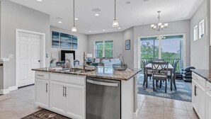 A spacious kitchen with a large island, modern pendant lights, and a dining area with a view. - Stay in comfort at Landings 126 in Placida: a spacious 3BR retreat! (Placida)