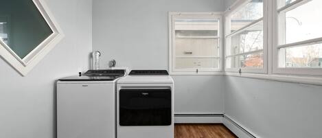 Eine kompakte Küche mit Kühlschrank, Herd und Backofen. Ein Fenster bietet Blick ins Freie.