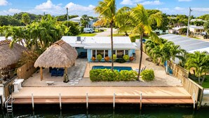 Ein Haus mit Pool, Steg und einem strohgedeckten Gebäude.