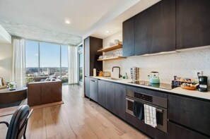 Cocina moderna con armarios oscuros, un ventanal y vista a la ciudad.