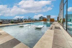 Ein Pool auf dem Dach mit Liegestühlen und Blick auf die Stadt.