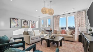 A modern living room with a sectional sofa, a coffee table, and artwork on the walls. - 2 Homes | 24 Guests | Rooftop Hot Tub Fire Pit (Nashville)