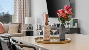 A table with a bottle of champagne, two glasses, and a vase with flowers. - 2 Homes | 24 Guests | Rooftop Hot Tub Fire Pit (Nashville)