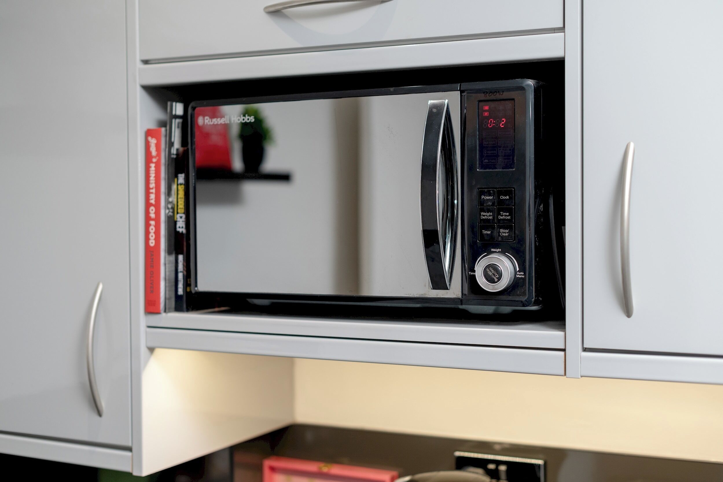 A microwave in a kitchen cabinet.