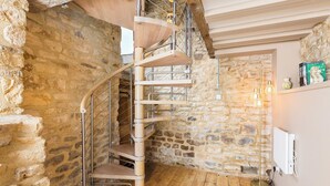 Eine Wendeltreppe in einem Raum mit Steinwänden, Holzboden und einem Heizkörper an der Wand.