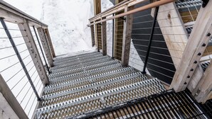 A metal staircase with a metal railing, leading up a snowy slope.