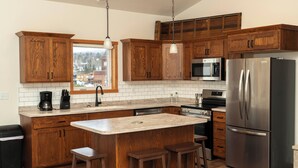 A modern kitchen with wooden cabinets, stainless steel appliances, and a large island with bar stools.