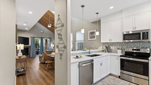 A modern kitchen with white cabinets, stainless steel appliances, and a tiled backsplash. - Tides & Timber by Avantstay Lakeside Retreat + Hot Tub + Kayaks + Paddleboard + Bikes Near Beach (Rockaway Beach)