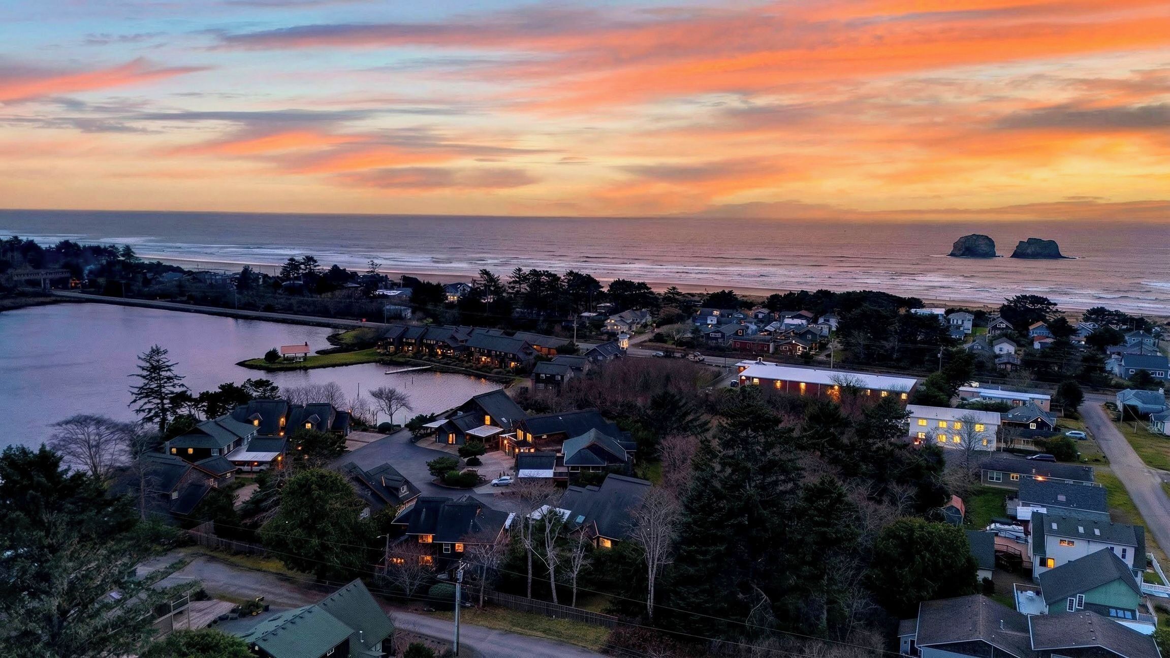 A coastal residential area with houses, a lake, and a sunset view.