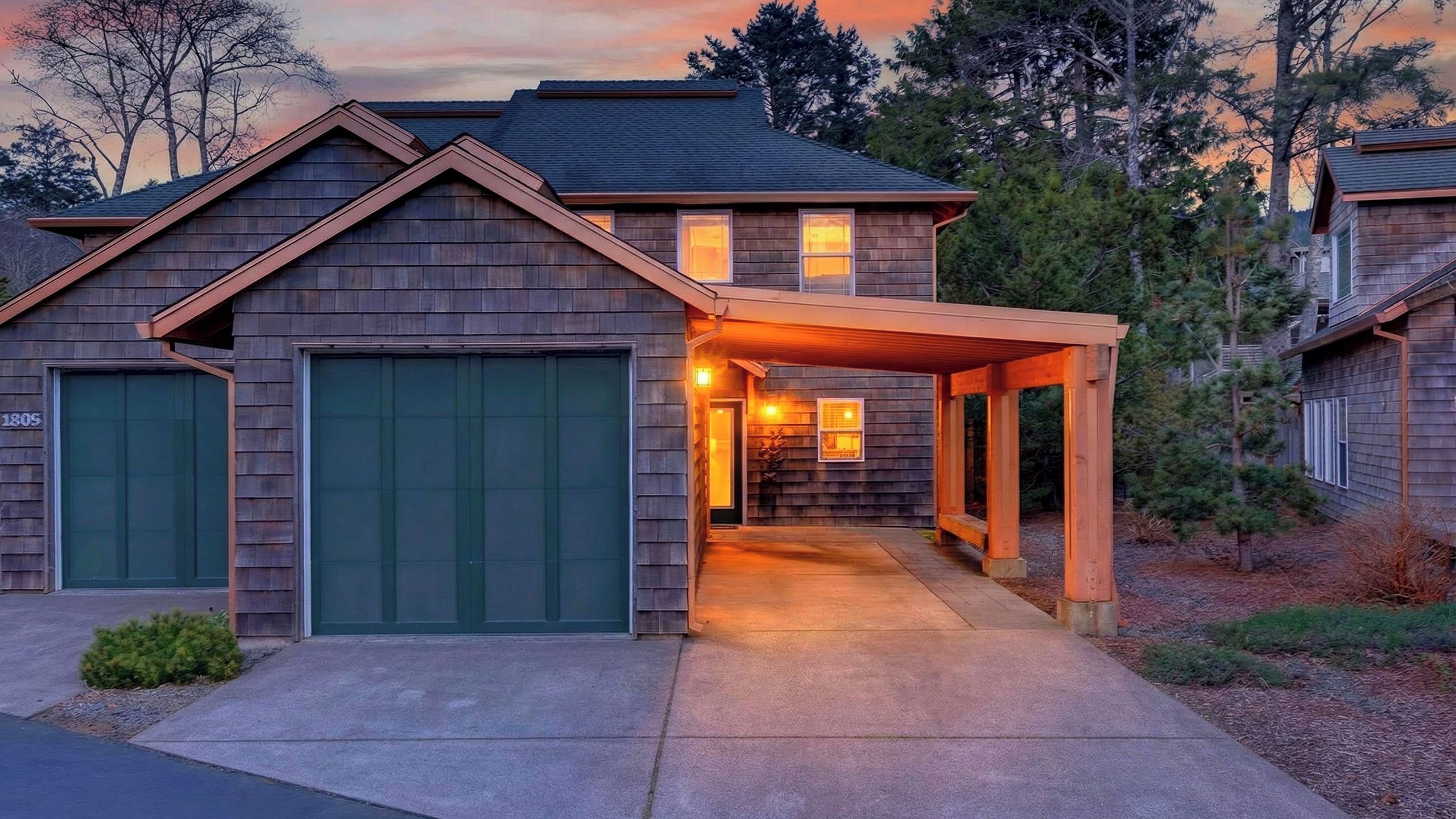 Ein zweigeschossiges Haus mit überdachter Veranda und Garage.