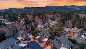 A residential area with houses, a driveway, and a mountain backdrop. - Tides & Timber by Avantstay Lakeside Retreat + Hot Tub + Kayaks + Paddleboard + Bikes Near Beach (Rockaway Beach)