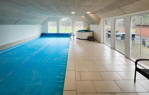 An indoor swimming pool with a blue floor, large windows, and a sauna. - Lovely home in Ulfborg with sauna (Ulfborg)