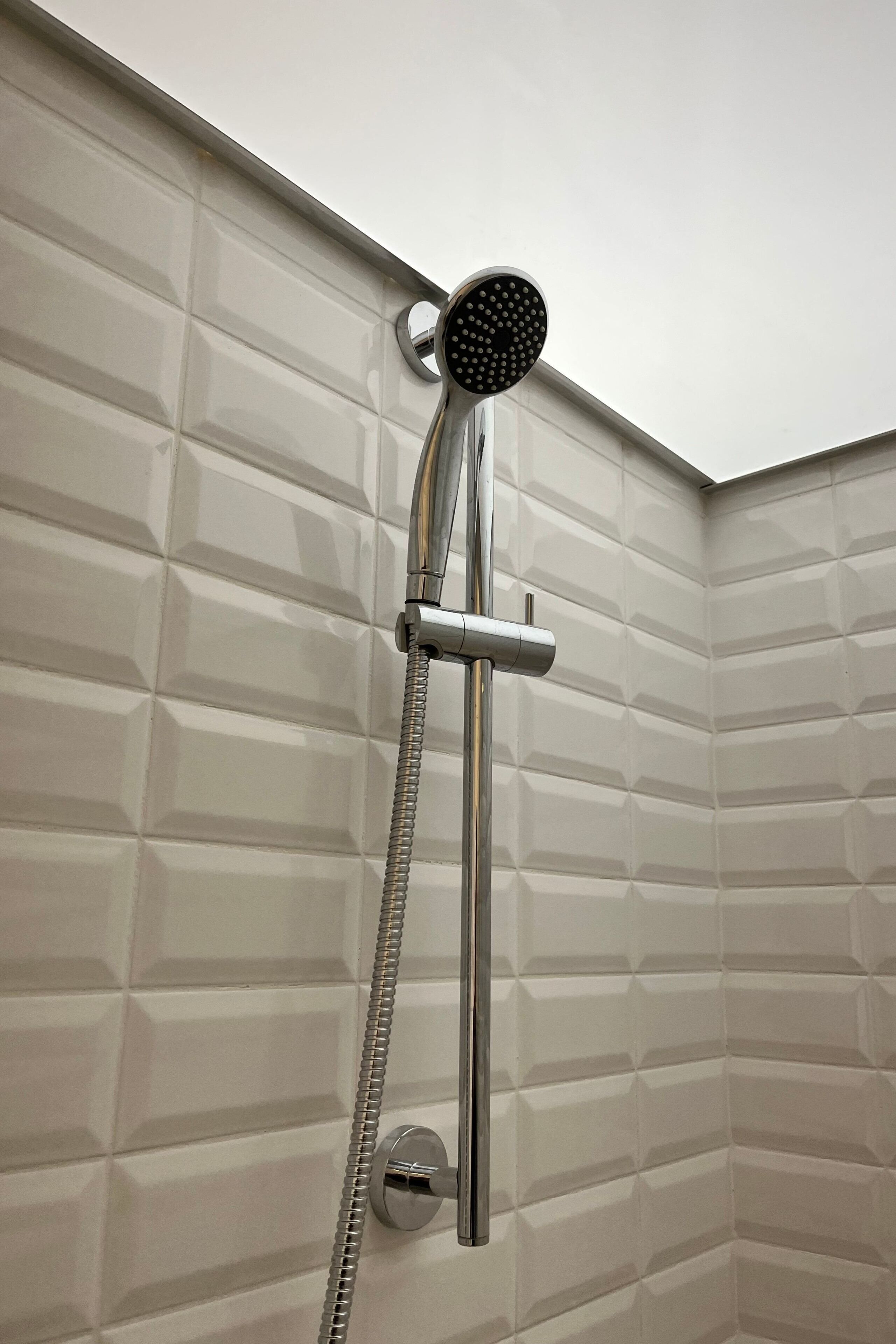A shower with a handheld showerhead and a fixed wall-mounted showerhead.