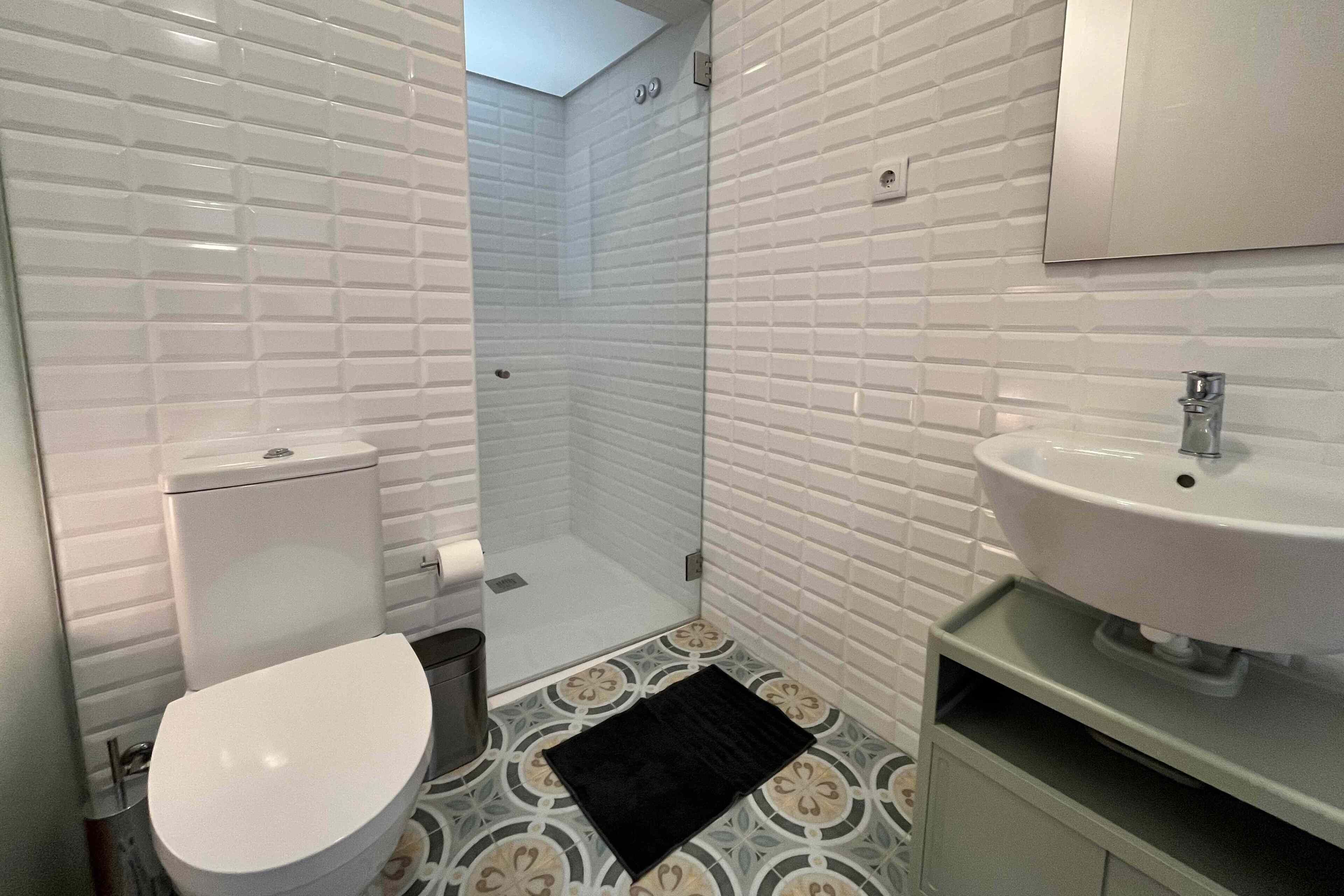 A bathroom with a toilet, a sink, and a shower area.