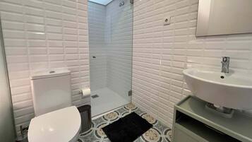 A bathroom with a toilet, a sink, and a shower area.
