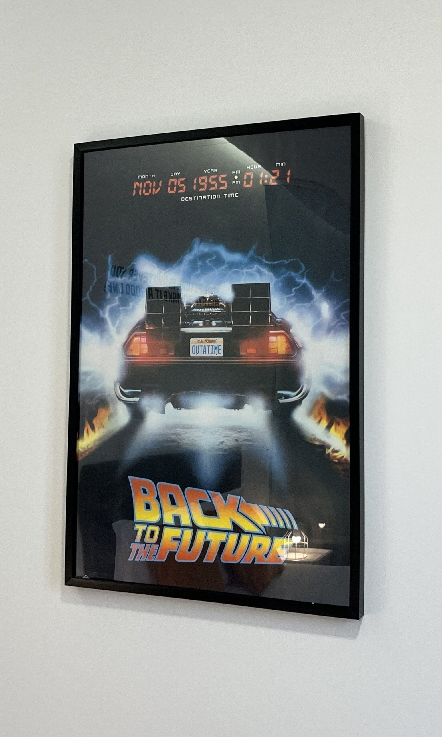 A movie poster for "Back to the Future" featuring a car with a license plate reading "DUTATIME" and a lightning storm in the background.