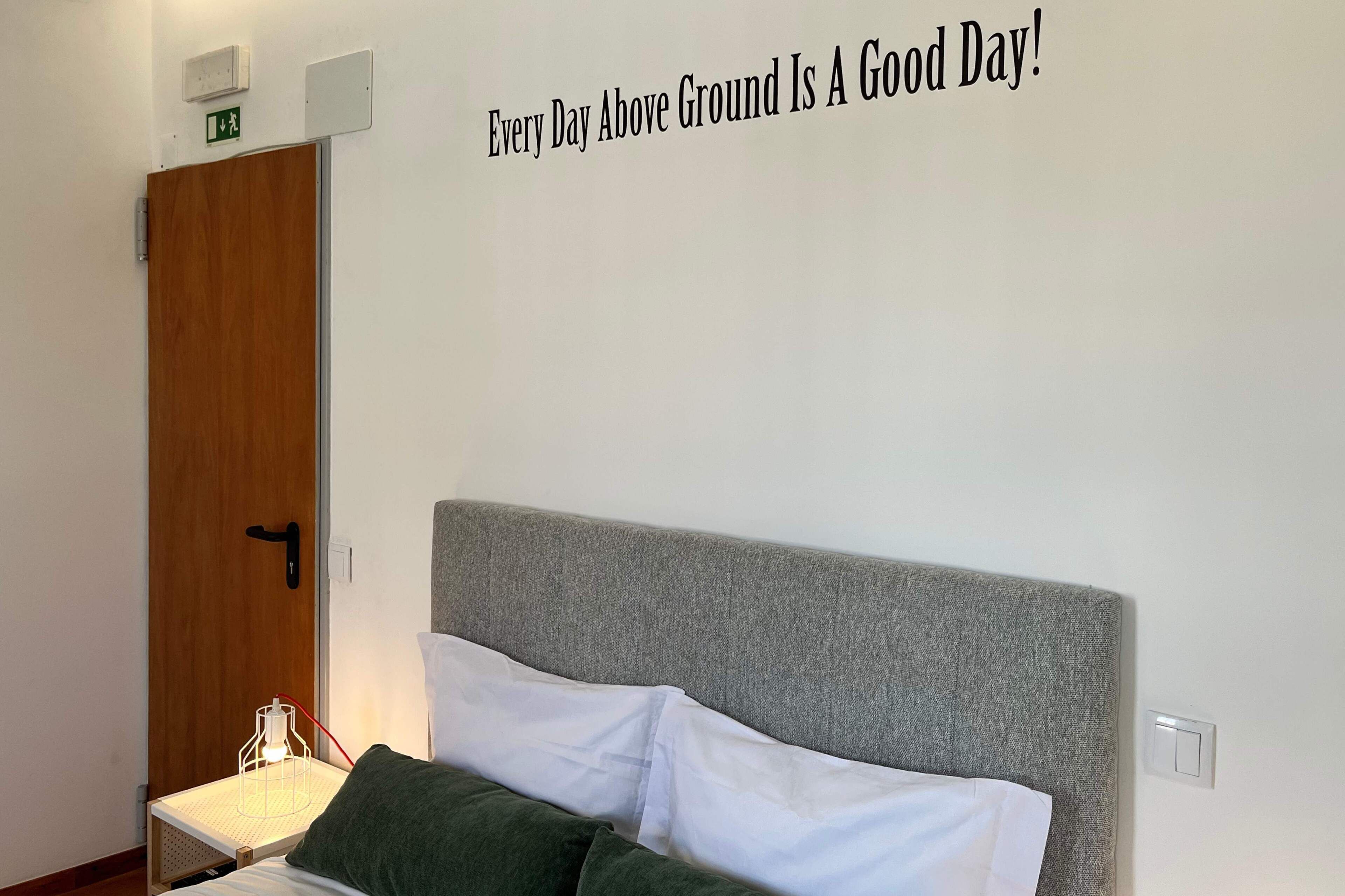 A bedroom with a bed, a bedside table, and a wall sign.