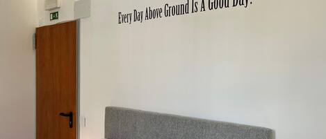 A bedroom with a bed, a bedside table, and a wall sign.