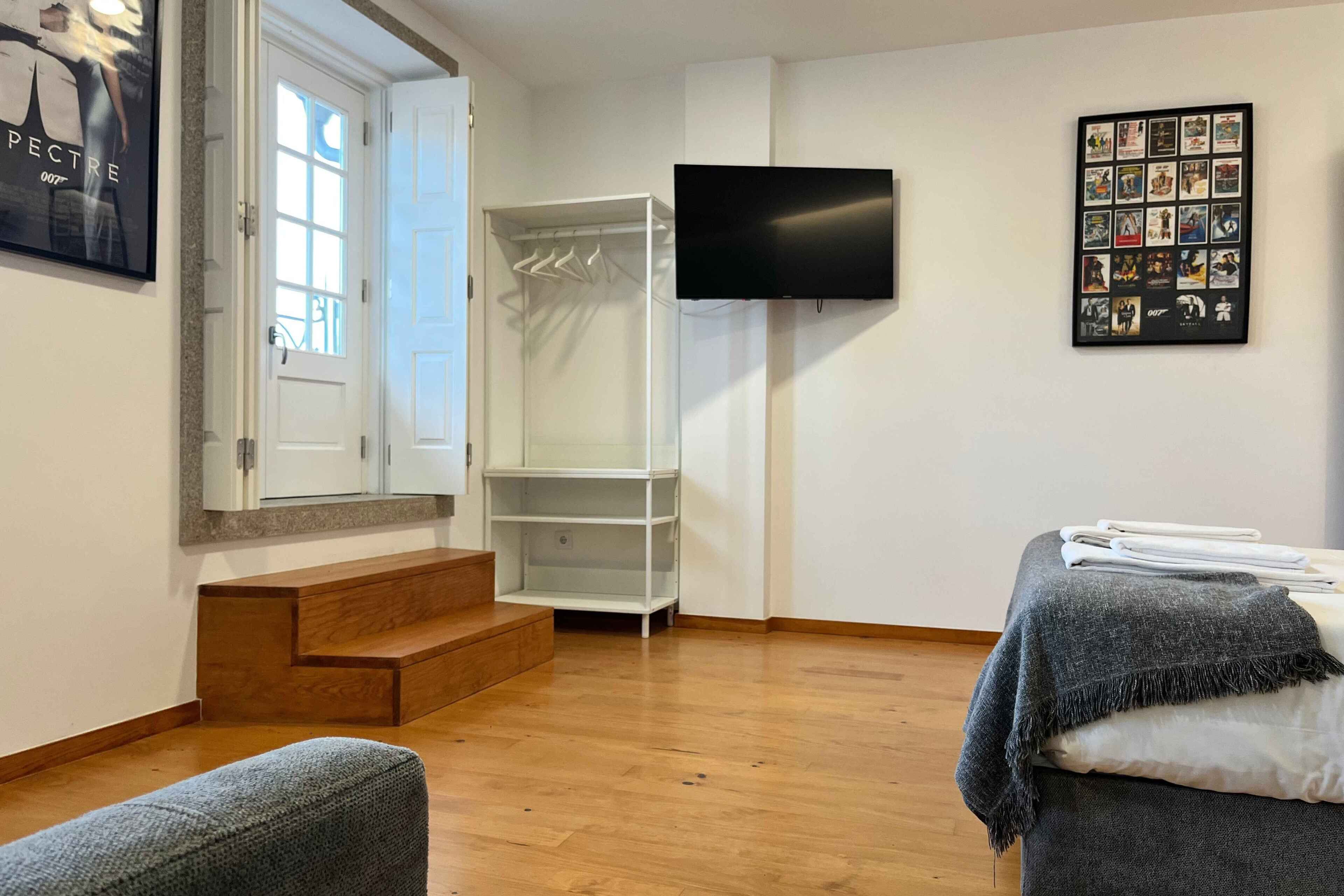 Une pièce moderne avec un plancher en bois, un canapé gris, un téléviseur fixé au mur et un ensemble de photos encadrées.
