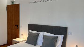 Una habitación de hotel con una cama, dos lámparas de noche, una puerta de madera y un letrero en la pared.