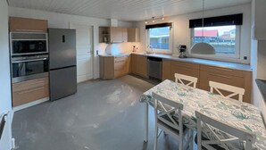 Eine kompakte Küche mit Essbereich, ausgestattet mit Kühlschrank, Backofen, Spüle und einem Fenster mit Blick.