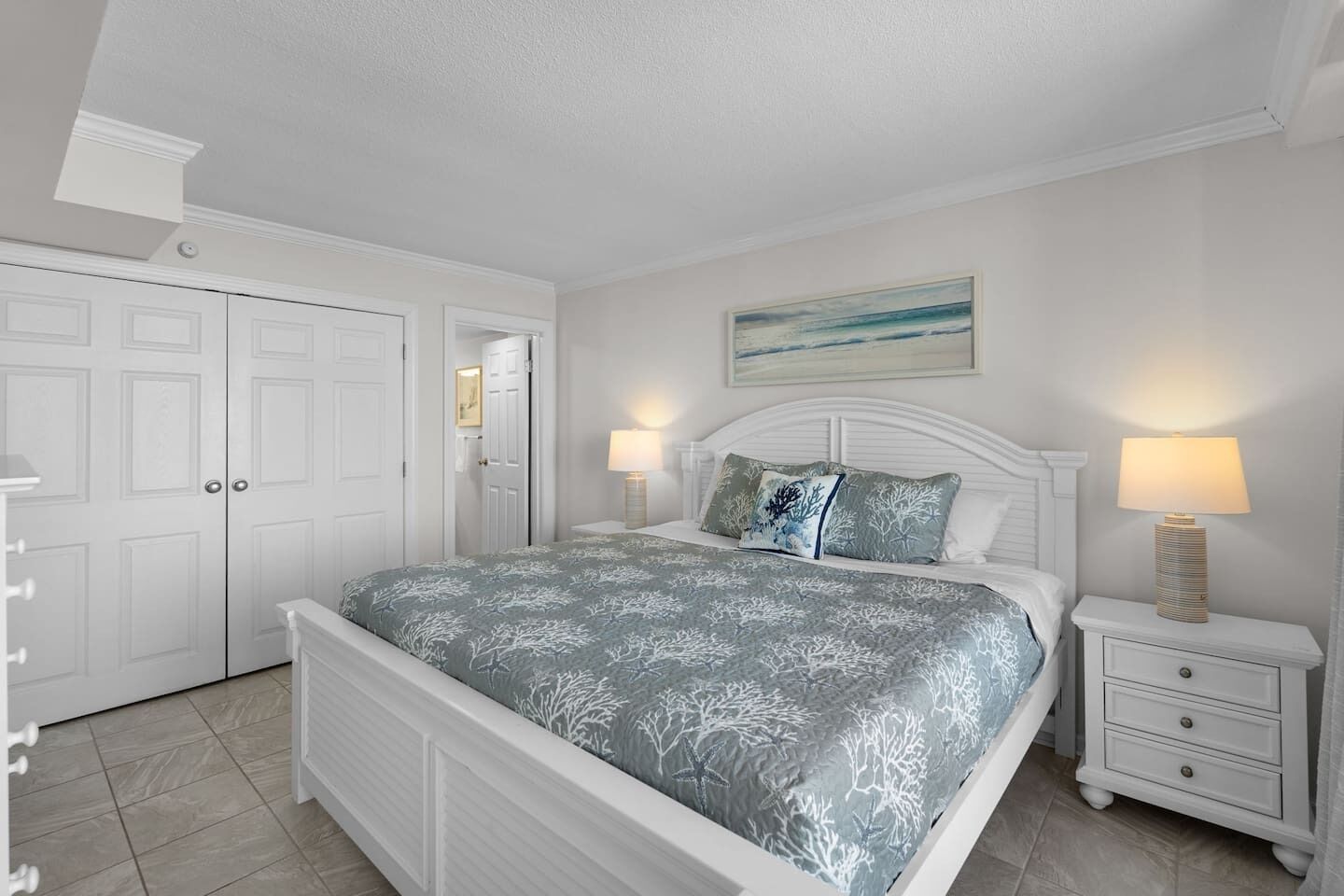 A bedroom with a bed, nightstands, a dresser, and a door.