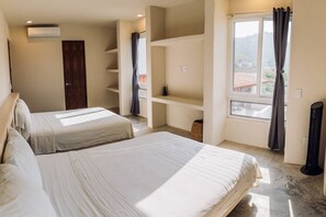 A hotel room with two beds, a window with curtains, a built-in shelf unit, and an air conditioning unit. - Private Ocean View Retreat with Pool | Luxury HOM (Troncones)