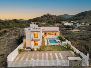 A modern two-story house with a swimming pool, surrounded by a landscaped garden and a view of hills. - Private Ocean View Retreat with Pool | Luxury HOM (Troncones)