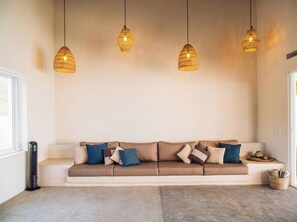 A modern living room with a beige sofa, patterned cushions, and hanging pendant lights. - Private Ocean View Retreat with Pool | Luxury HOM (Troncones)