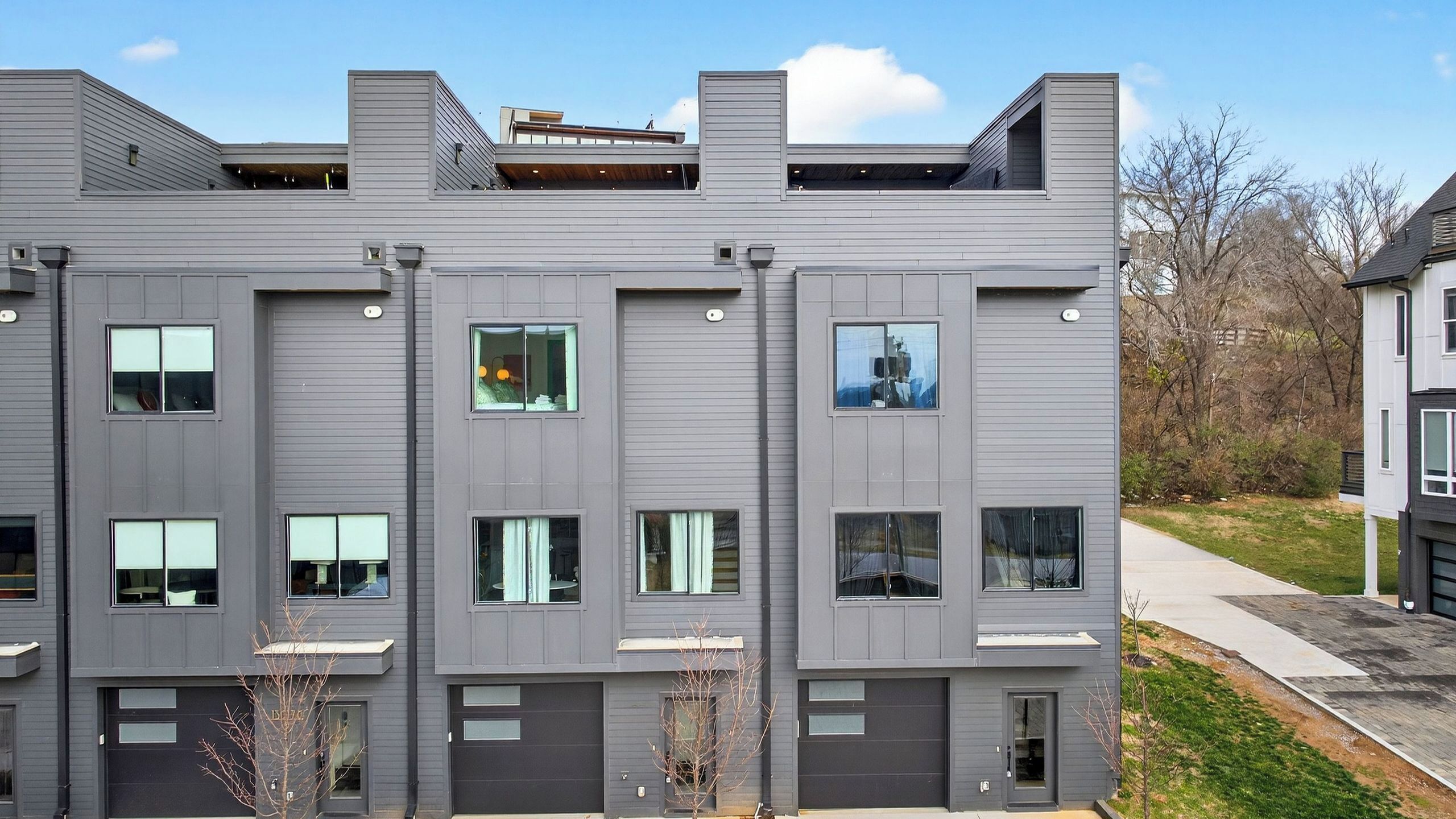 A modern multi-story building with a flat roof, large windows, and a garage entrance.