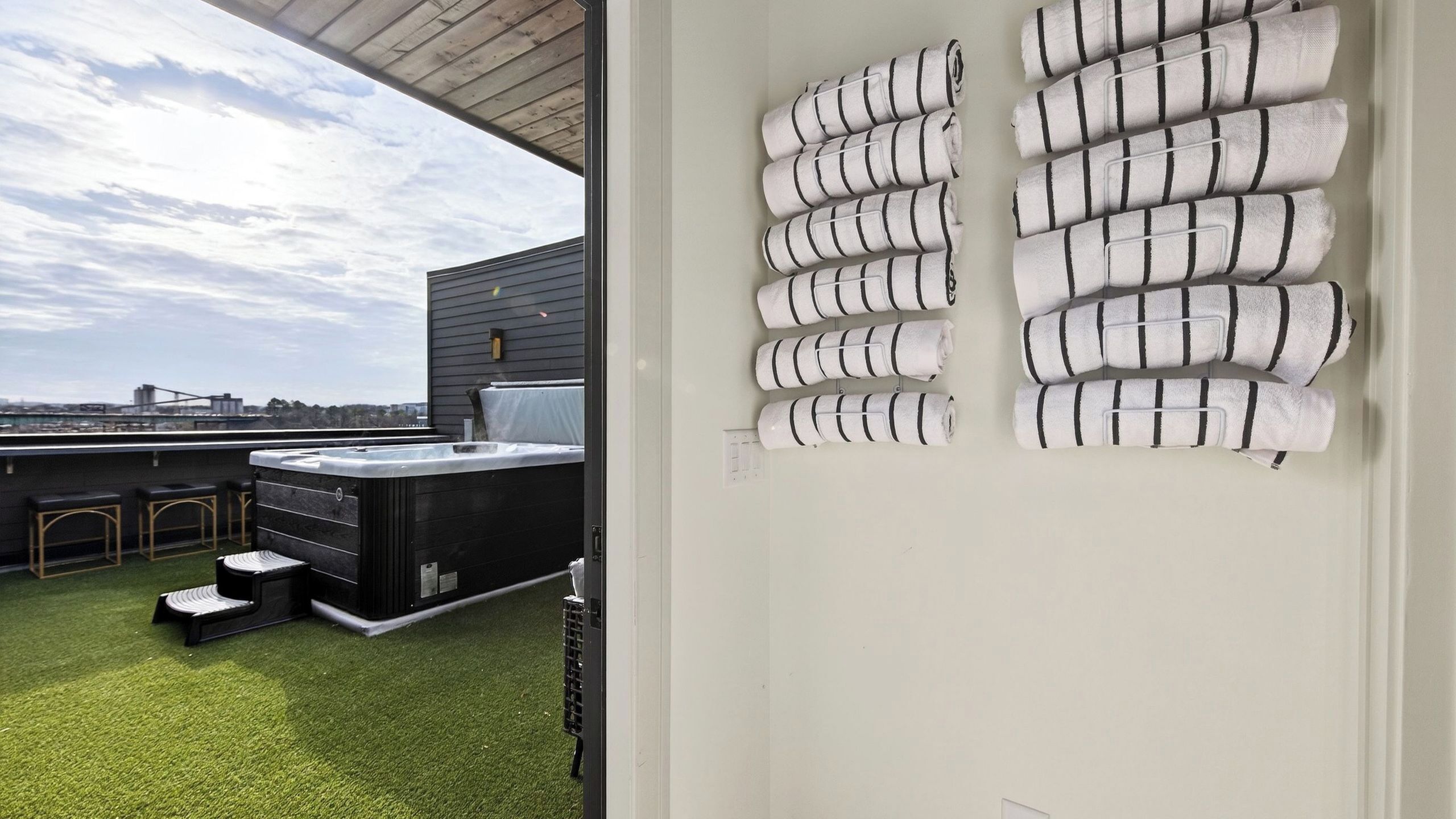 A rooftop terrace with a hot tub, bar area, and neatly arranged towels.