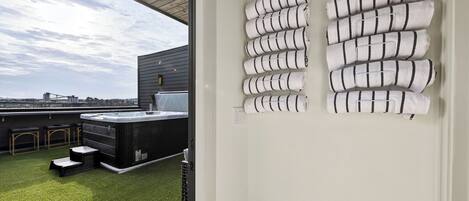 A rooftop terrace with a hot tub, bar area, and neatly arranged towels.