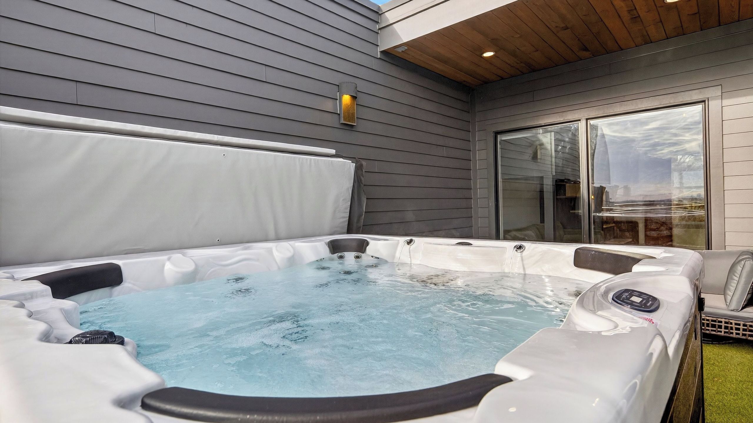 A hot tub with a wooden ceiling and a glass door leading to a patio.