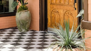 A wooden door with a glass panel, a large potted plant, and a checkered floor. - Salt Ranch Hotel (Nashville)