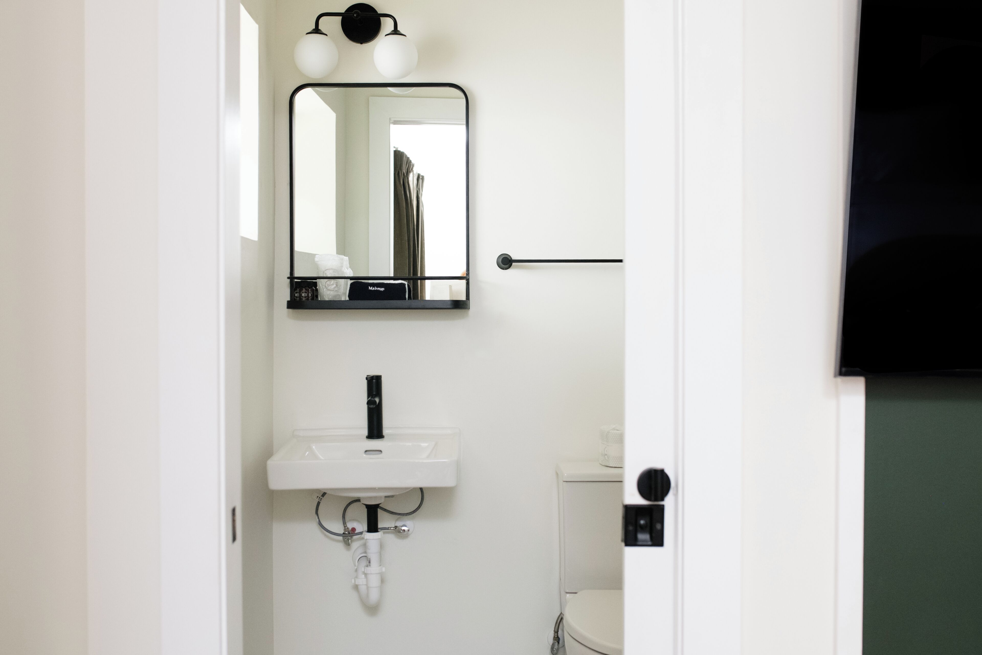 Une salle de bain avec un lavabo blanc, un miroir et des toilettes.