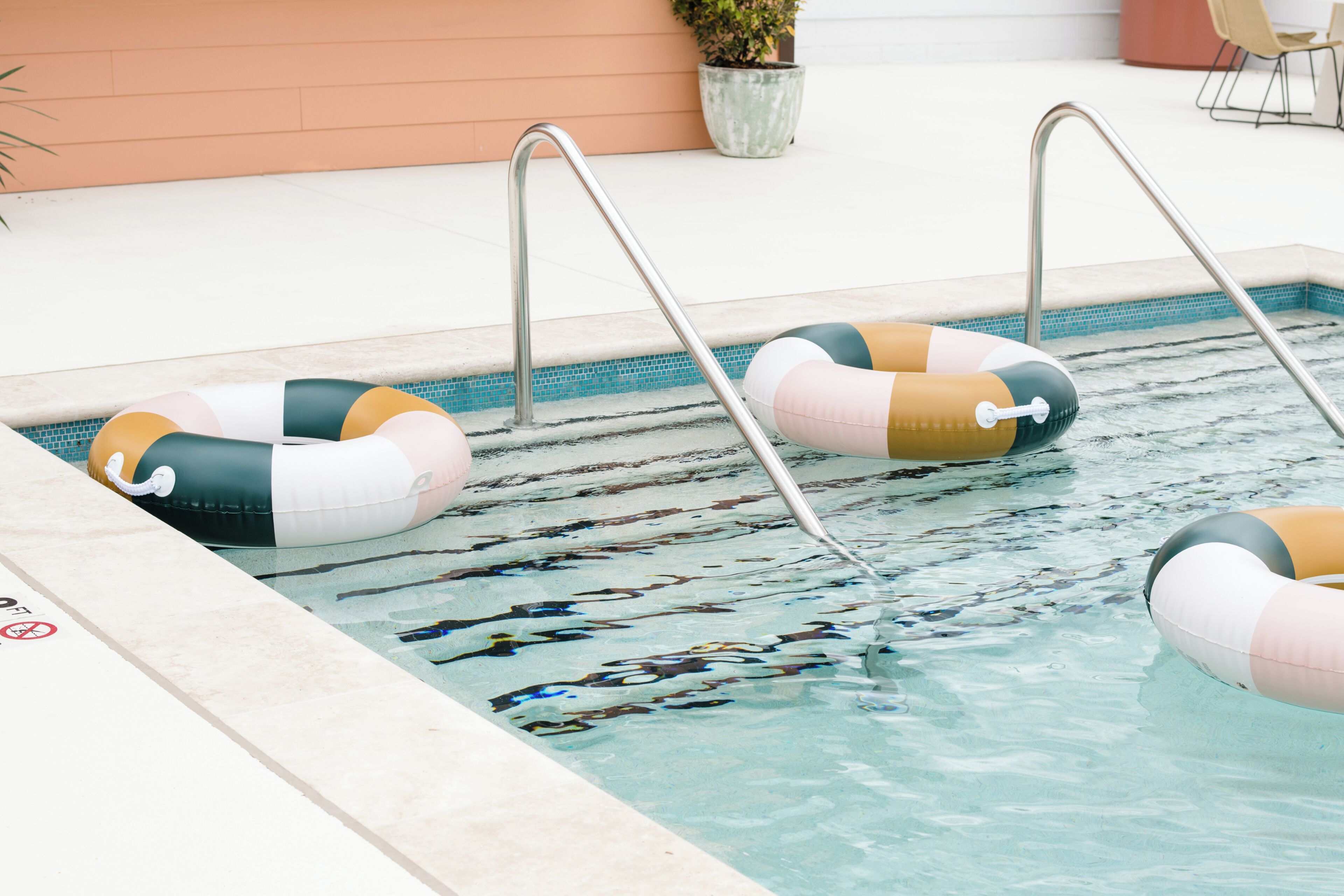 Una piscina con dos flotadores inflables y escaleras de metal.