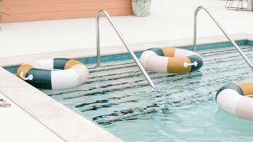 Una piscina con dos flotadores inflables y escaleras de metal.