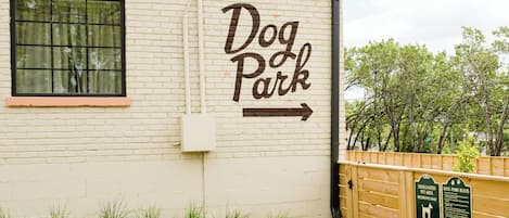 A building labeled 'Dog Park' with a directional arrow, a wooden fence, and a sign detailing park rules.