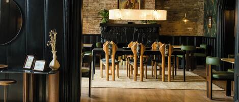 Un restaurant avec des chaises en bois, un mur noir et une cheminée.
