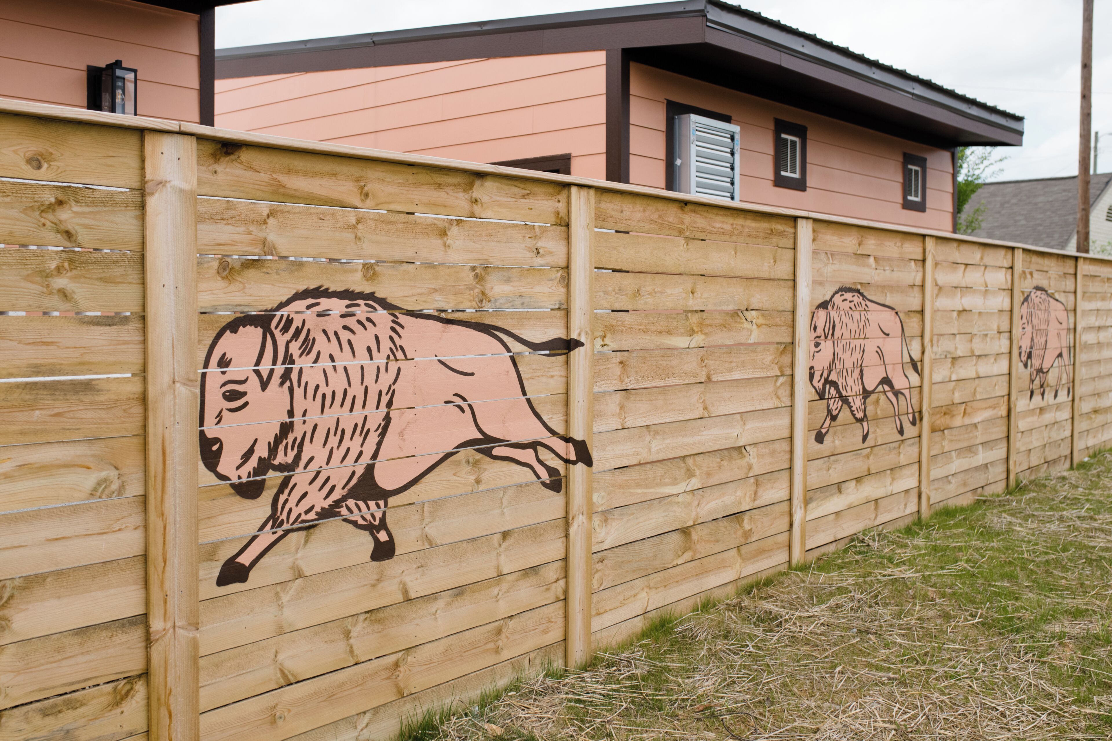 Une clôture en bois ornée de peintures murales représentant des animaux.