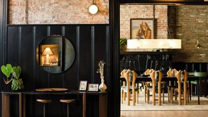 A bar area with a round mirror, a small table with stools, and a brick wall. - Salt Ranch Hotel (Nashville)