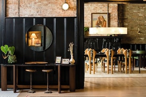Un área de bar con un espejo redondo, una pequeña mesa con taburetes y una pared de ladrillo.