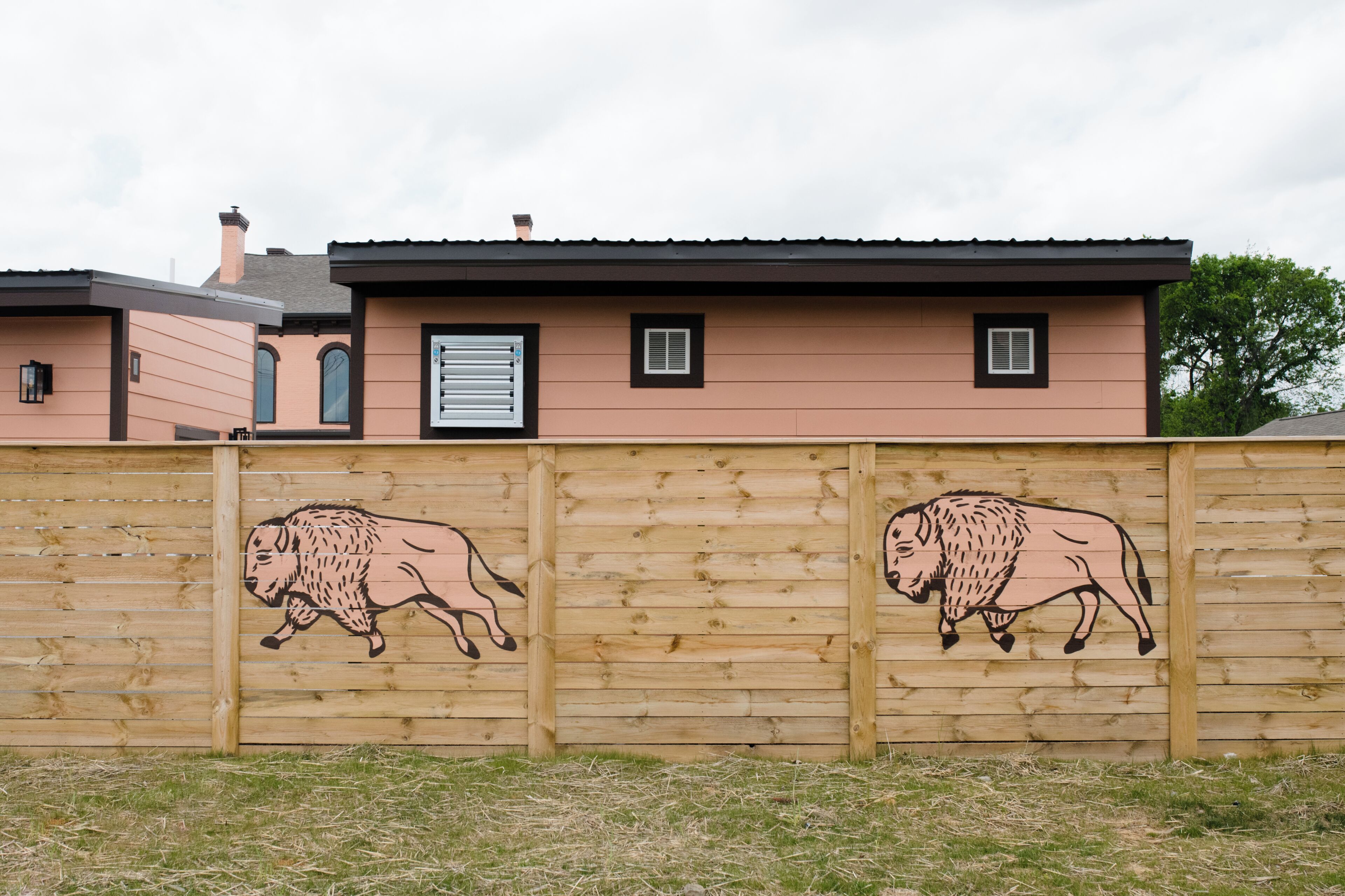 Ett hus med ett staket av trä, på vilket det finns två illustrationer av bisonoxar.