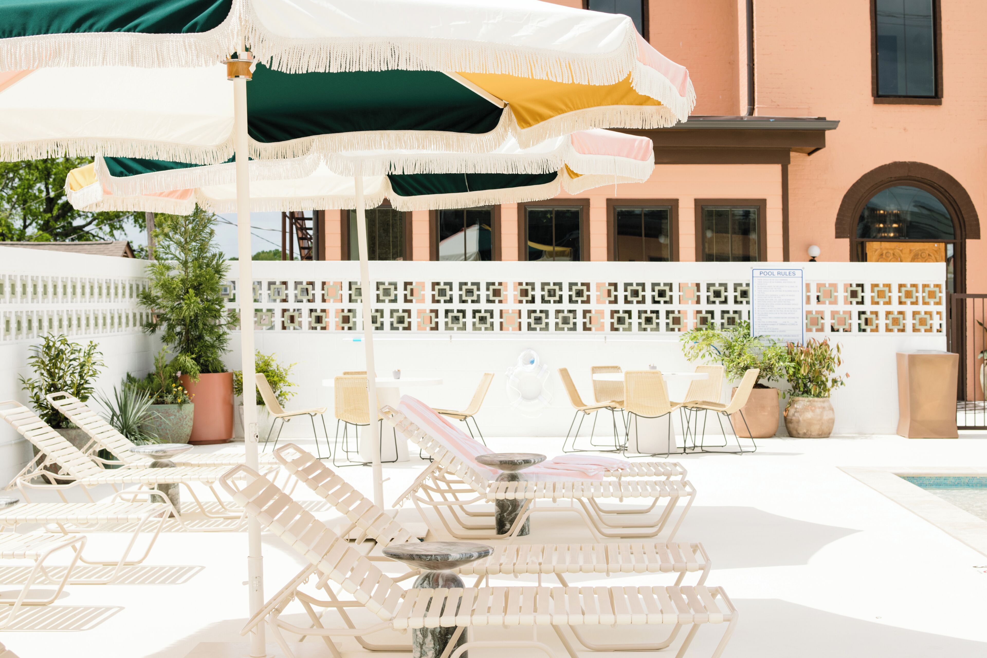A poolside area with lounge chairs, umbrellas, and a tiled wall.