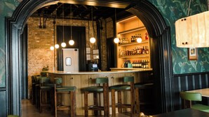 A bar area with wooden stools, a counter, and a brick wall. - Salt Ranch Hotel (Nashville)