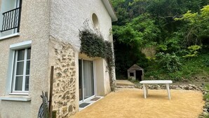 Ein Haus mit einer Stein-Fassade, einem Balkon und einem Garten mit einer Bank.